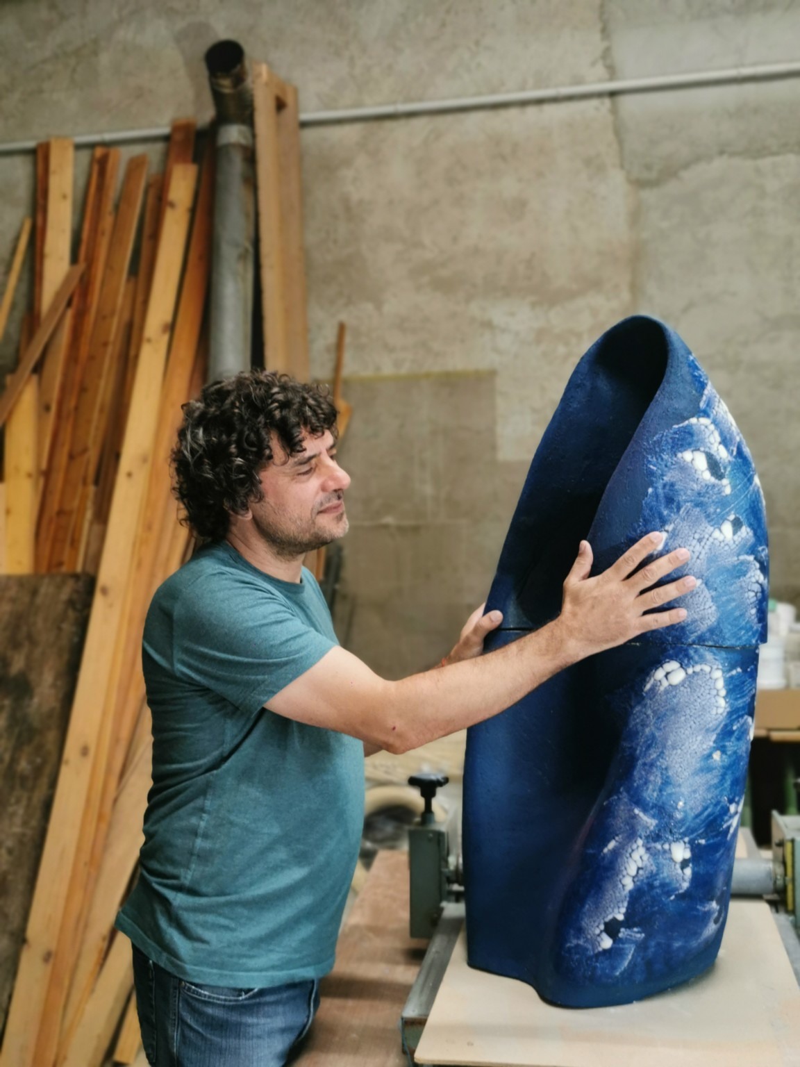 David Fernández ajustant una escultura ceràmica blava de gran format al taller